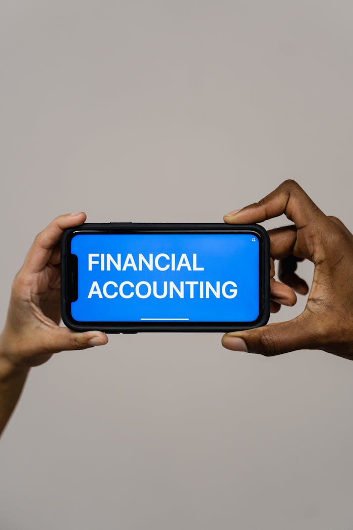 Two people holding a smartphone displaying the text 'Financial Accounting'.